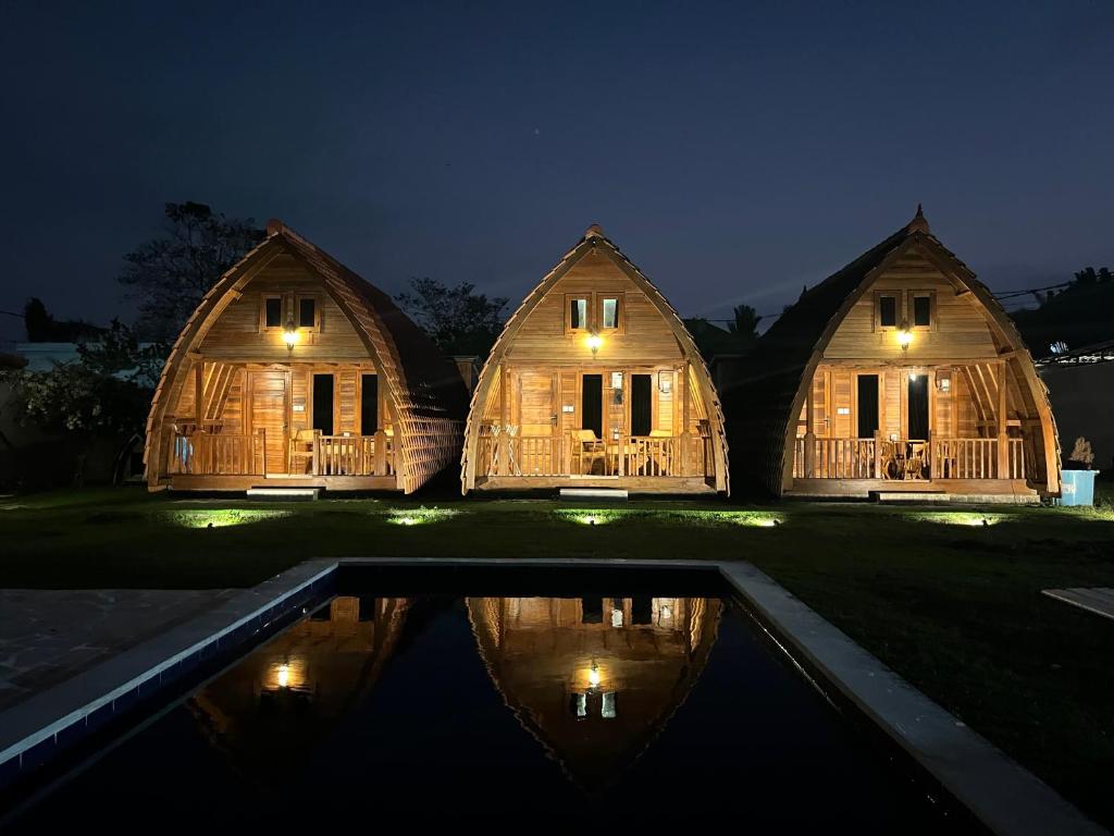 Villa Aiden Bungalow 1 Familiale Ungasan في أونغاسان: زوجان من المنازل مع انعكاس في الماء في الليل