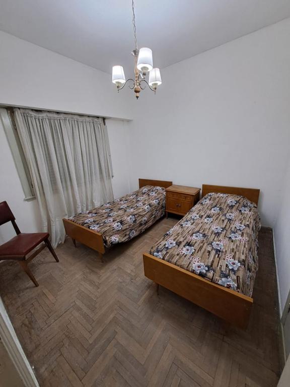 1 Schlafzimmer mit 2 Betten, einem Stuhl und einem Kronleuchter in der Unterkunft Tucumán y Colón in Mar del Plata