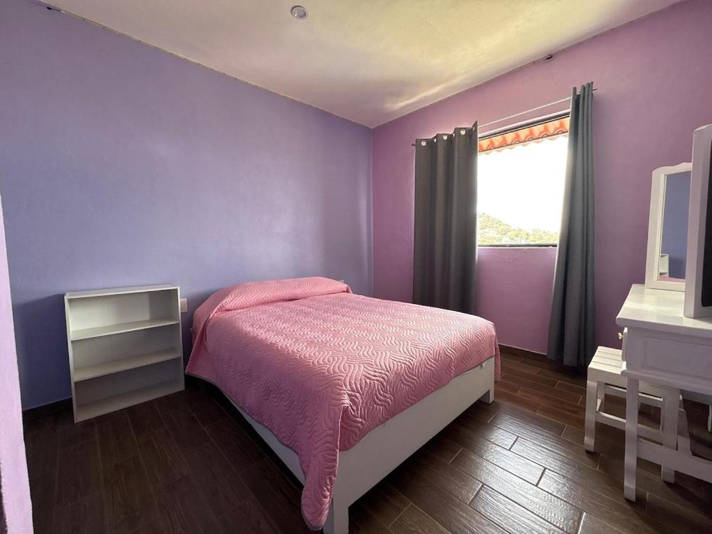een paarse slaapkamer met een bed en een raam bij Silver Mountain House in Taxco de Alarcón