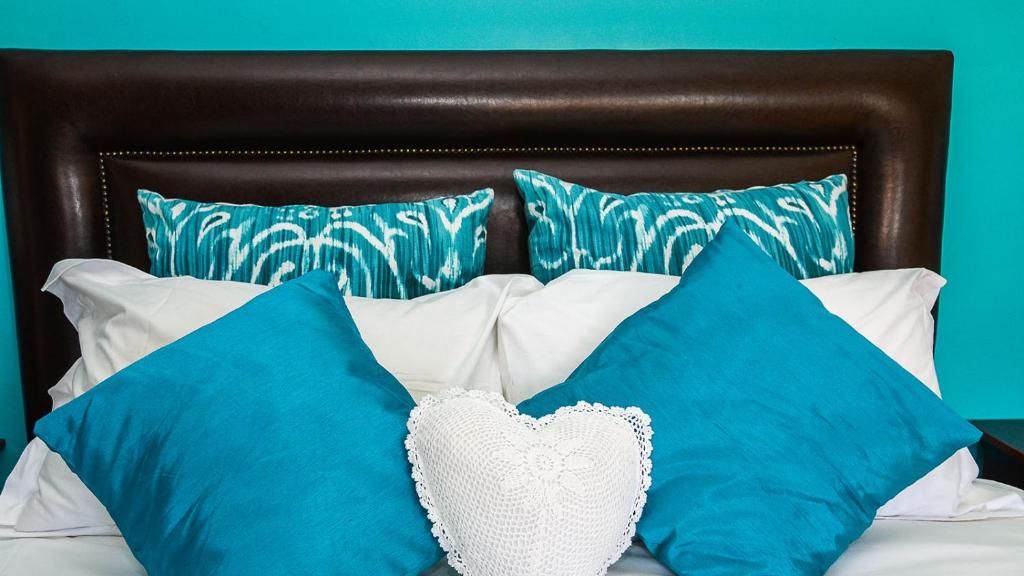 Una cama con almohadas azules y blancas. en Beth El Guesthouse en Brackenfell