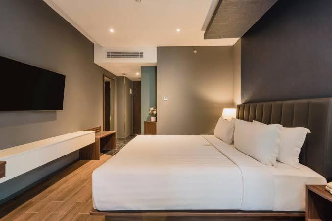 ein Schlafzimmer mit einem großen weißen Bett und einem Flachbildfernseher in der Unterkunft Oyo Apartment Deluxe by Egi in Jakarta