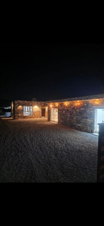 a stone building with lights on it at night at Climbing Guest House Jebel Shams in Dār Sawdāʼ