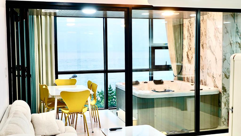 sala de estar con bañera, mesa y sillas en 안목을높이다 펜션, en Kyŏnso