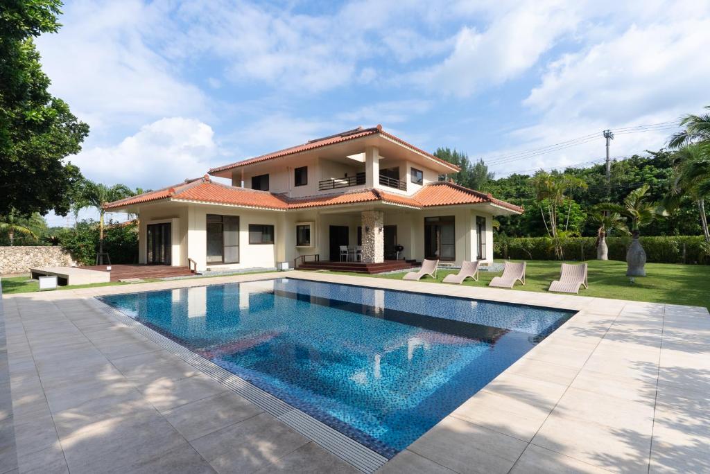 a villa with a swimming pool in front of a house at Ocean Front Villa Ishigakijima Ⅰ in Ishigaki Island