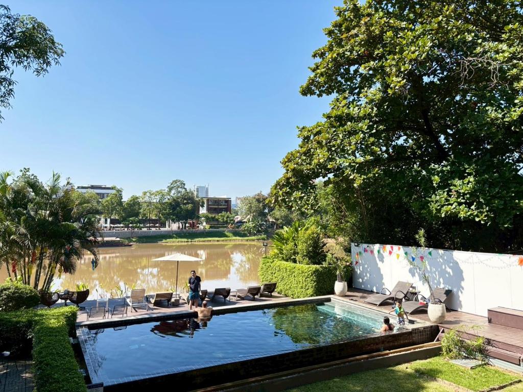 a man standing next to a swimming pool in a park at i-river chiangmai in Chiang Mai