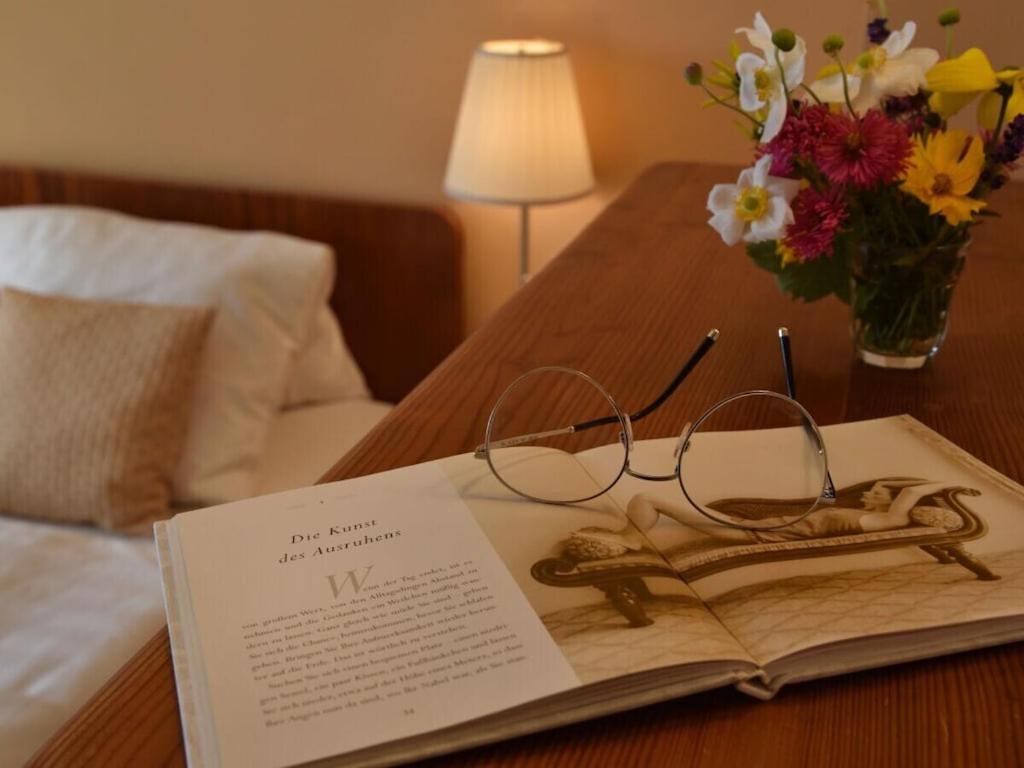 a book on a table with glasses and a vase of flowers at Holiday apartment with 1 bedroom in Aich