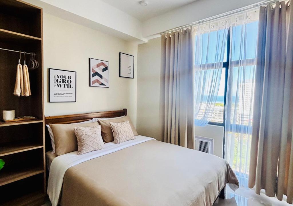 a bedroom with a bed and a large window at The Asher Mactan at Mactan Plains Residences in Mactan