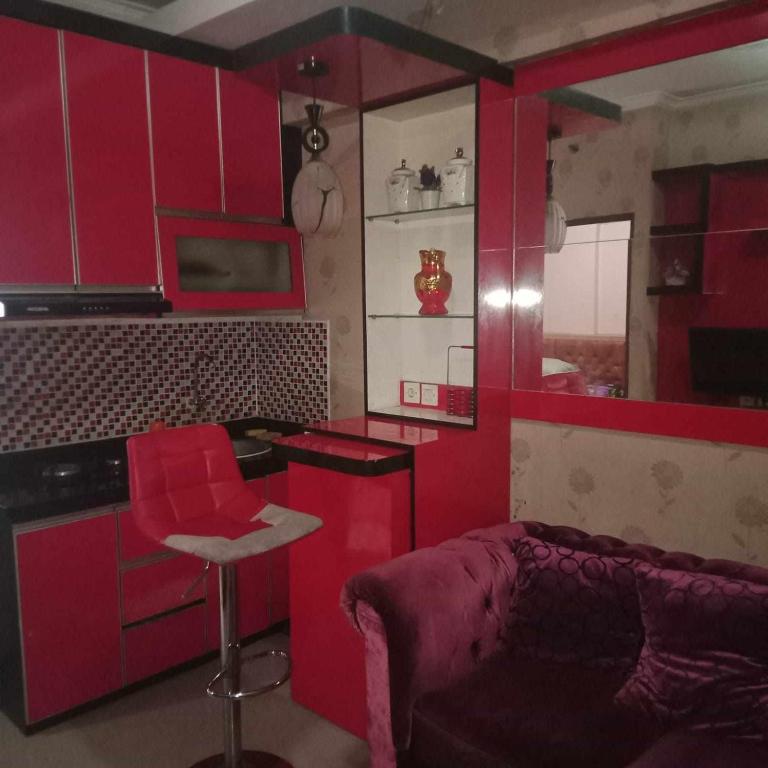 a kitchen with red cabinets and a red bar stool at Aparta Homestay in Pekayon Satu