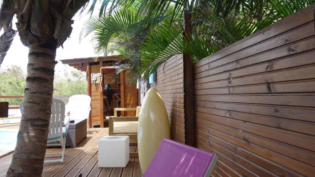 een terras met een surfplank en een tafel en stoelen bij Les Flibustiers in Sainte-Anne