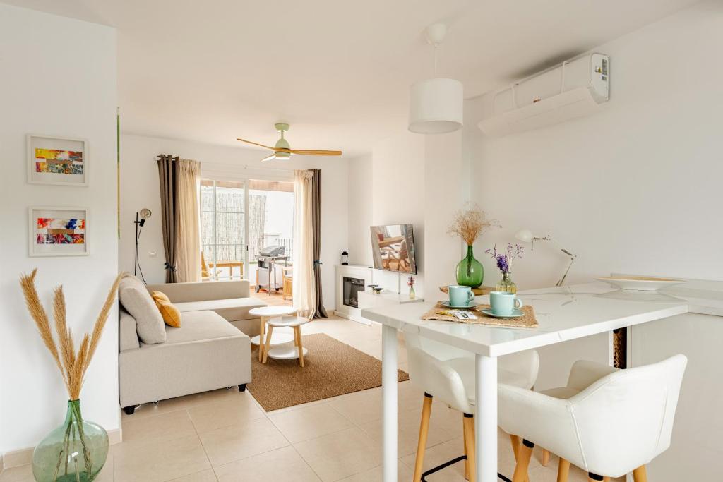 una cucina e un soggiorno con tavolo e sedie bianchi di Wonder Atic, with private terraces, jacuzzi and stunning views a Cómpeta