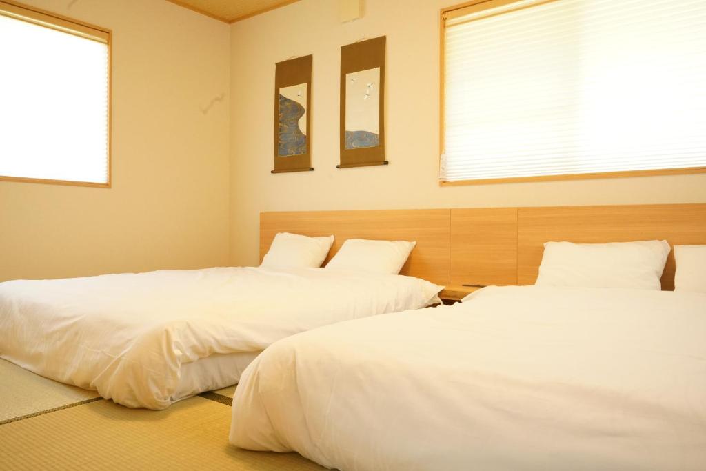two beds sitting next to each other in a bedroom at Private stay MIYAJIMA tonbo-AND in Hatsukaichi