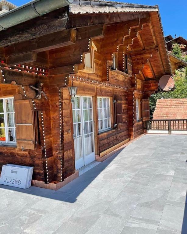 a log cabin with a white door on a patio at Charmantes Chalet mit Studio & Bergblick in Habkern