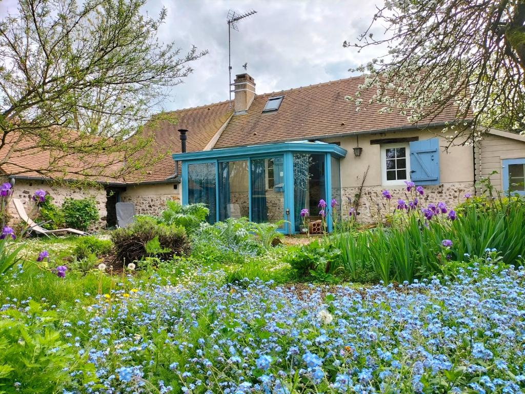 una casa con un giardino con fiori blu di Gîte des Cornettes a Écardenville-sur-Eure