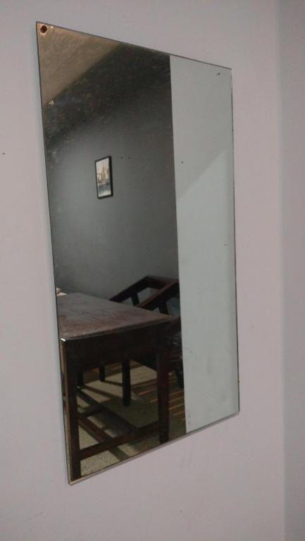 a mirror on a wall with a table in a room at Cherry On The Top Homestay with AC in one bedroom in Kolhapur