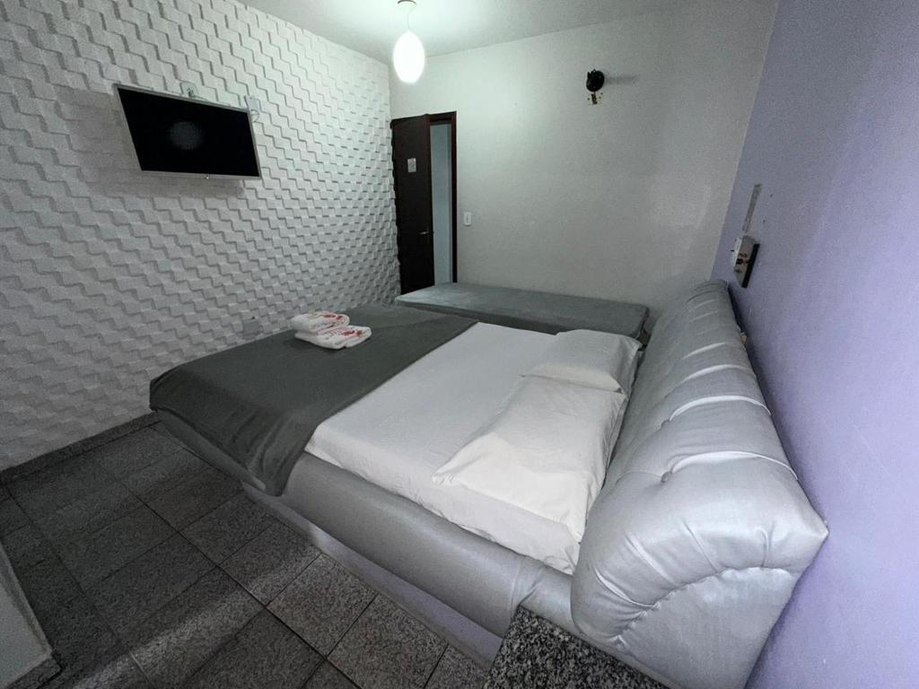 Cette chambre comprend un grand lit blanc et une télévision. dans l'établissement Caribe Palace Hotel Taguatinga, à Brasilia