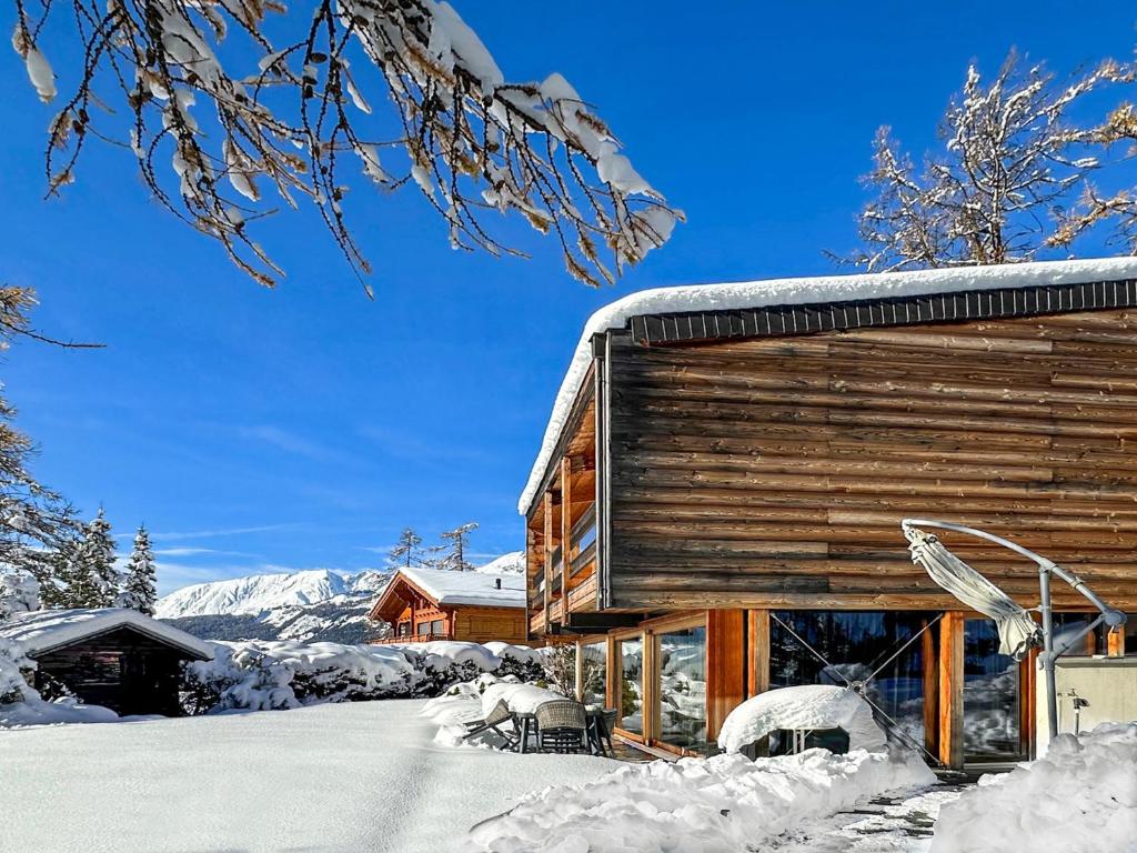 Una cabaña de troncos con nieve a un lado. en Crans Montana under the stars, en Crans-Montana