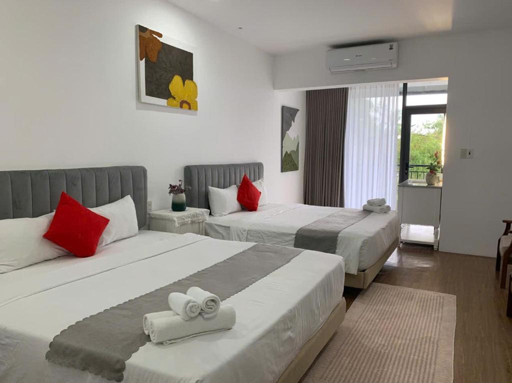 zwei Betten in einem Hotelzimmer mit roten Kissen in der Unterkunft The Dreamers Homestay in Hue