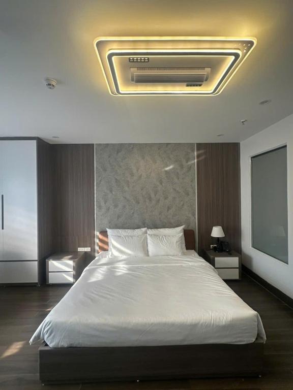 a bedroom with a large white bed with a ceiling at Elegant Hotel in Hanoi