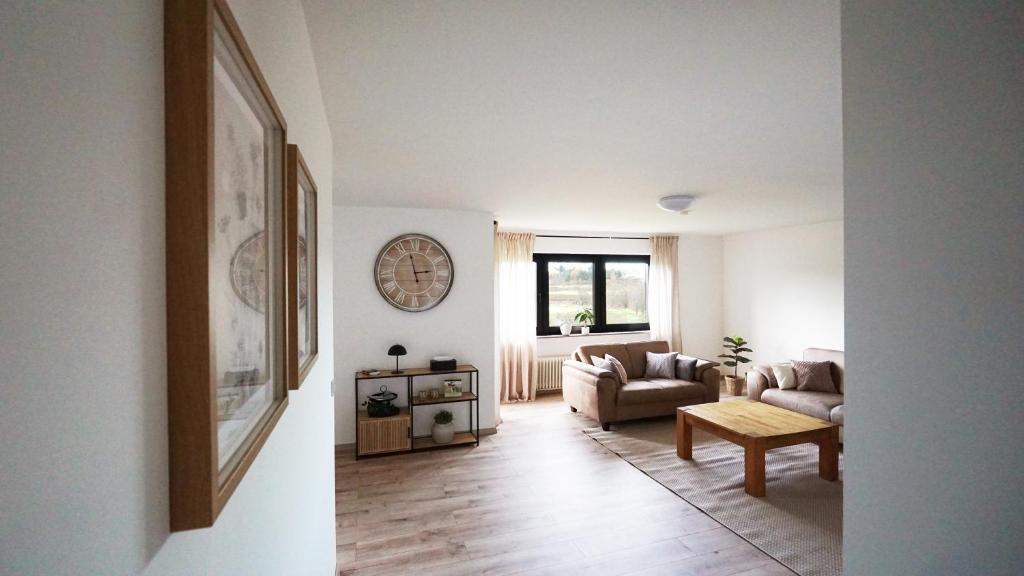een woonkamer met een bank en een klok aan de muur bij Apartment am Golfplatz in Mackenbach in Mackenbach