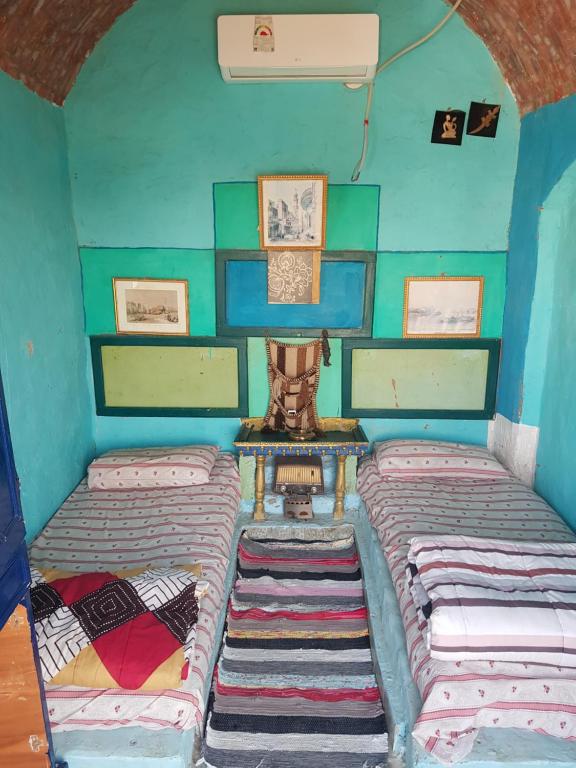 2 Betten in einem kleinen Zimmer mit blauen Wänden in der Unterkunft Seheil Antique House in Jazīrat Salūjah