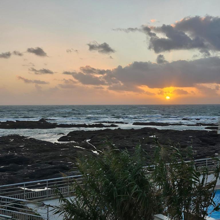 una puesta de sol en la playa con el océano en Premium Ocean View Studio, Balcony & Pool, en Les Sables-dʼOlonne