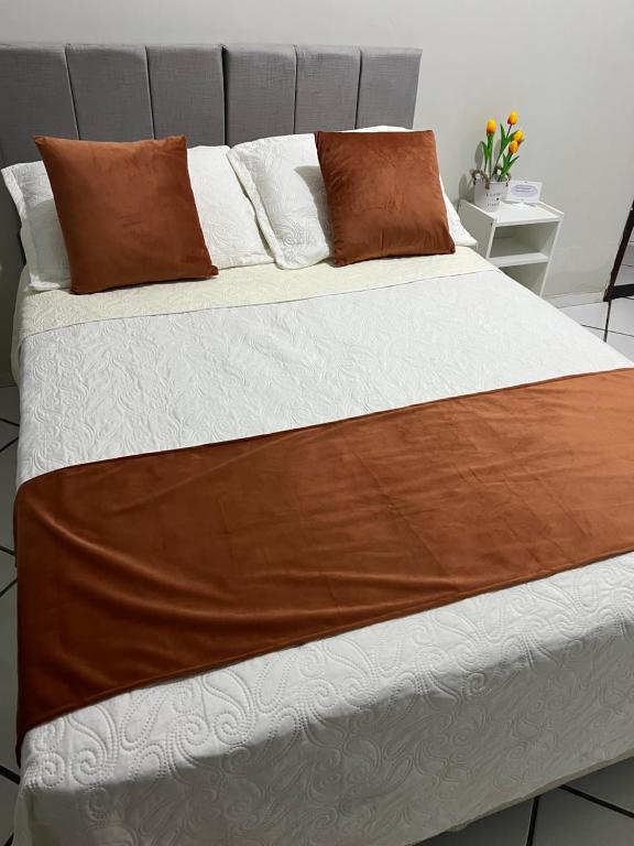 un grande letto con lenzuola e cuscini marroni e bianchi di Casa do umbuzeiro a Bom Jesus da Lapa