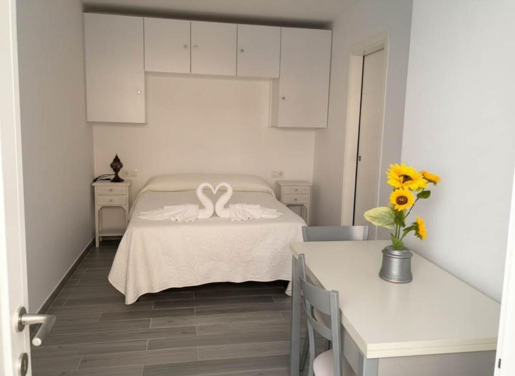 een witte slaapkamer met een bed met een zwaan erop bij Estudio cerca de la playa y del centro de conil in Conil de la Frontera