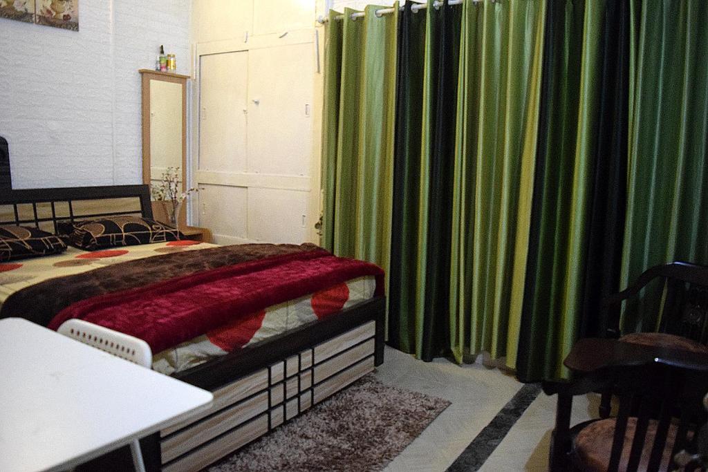 a bedroom with a bed and green curtains at Men-only COZYCORNER in Lucknow