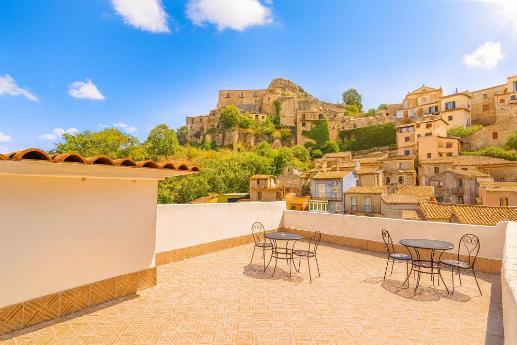 a patio with tables and chairs on a balcony with a mountain at Albergo Diffuso Borgo Santa Caterina "Vintage" in Castiglione di Sicilia