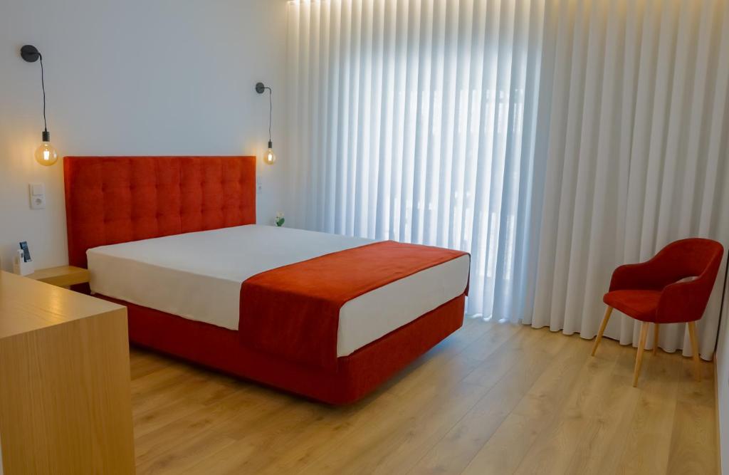 a bedroom with a large bed and a red chair at Coração de Viana AL in Viana do Castelo