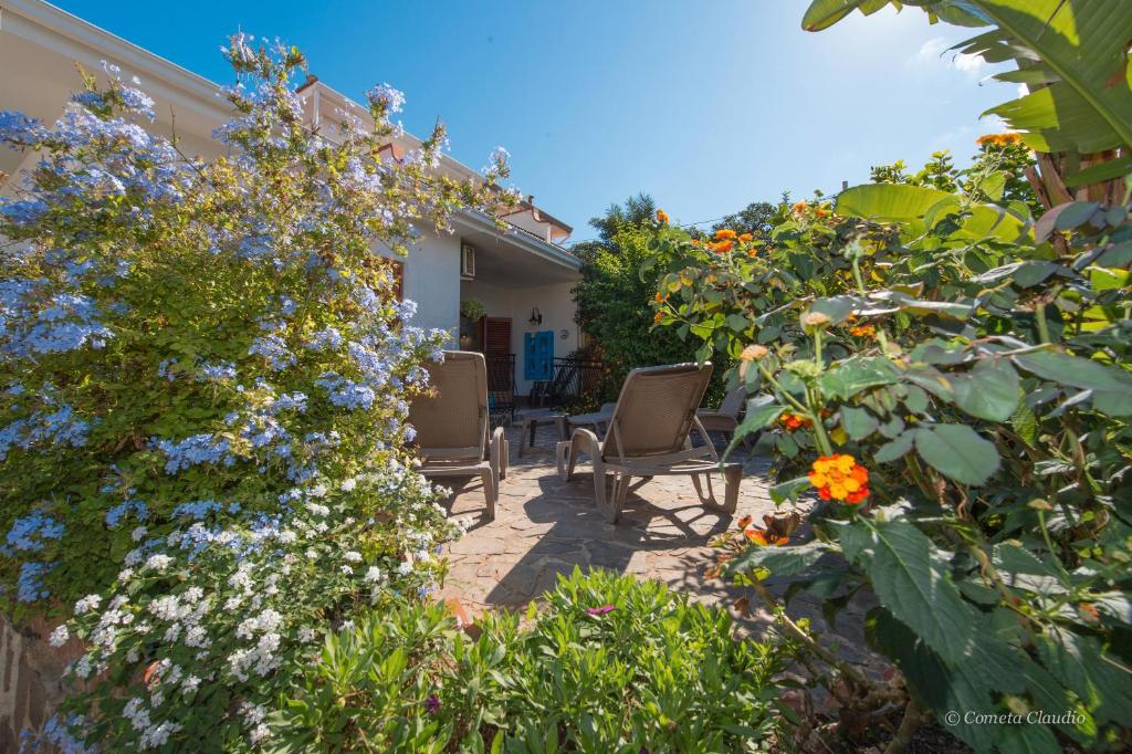 a garden with two chairs and flowers at Villa Alex Relax E Mare in Mondello