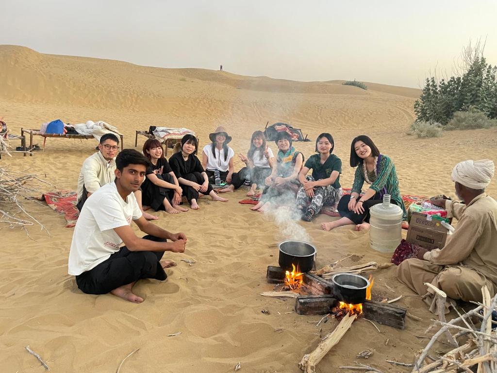 een groep mensen die rond een vuur in het zand zitten bij Osaka Desert Safari Camp in Jaisalmer