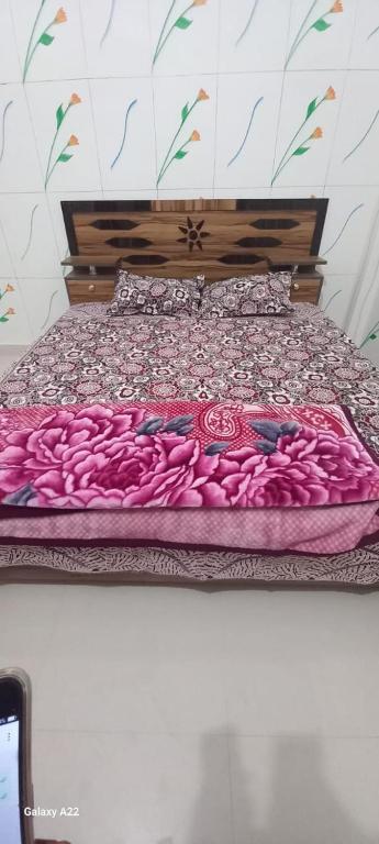 a bed with a pink comforter on it at Pawansut Dham in Naimishāranya