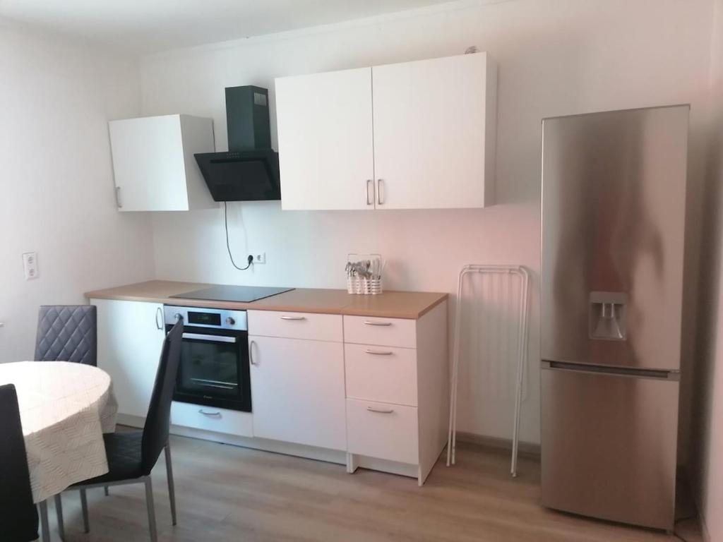 Una cocina con gabinetes blancos y una mesa y un refrigerador. en Strasbourg Pont de l'Europe, en Kehl am Rhein