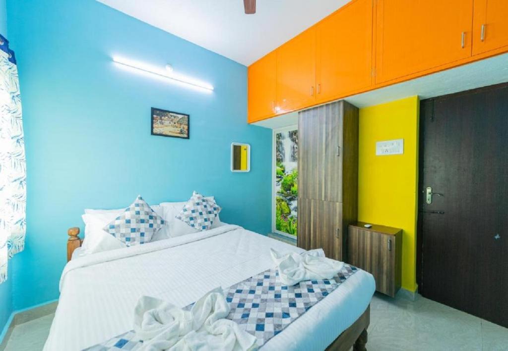 a bedroom with a bed with blue and yellow walls at RMP Home Stay in Puducherry