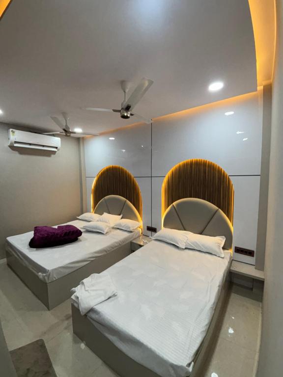 two beds in a room with two chairs at rk hotel in Ujjain