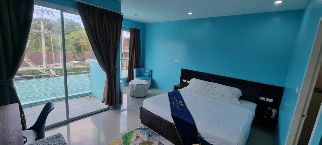 The Bedroom Kata Beach Phuket في شاطئ كاتا: غرفة نوم زرقاء مع سرير ونافذة كبيرة