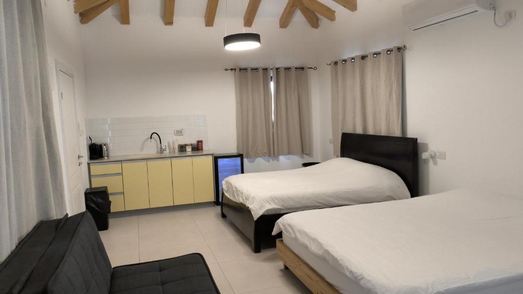 een hotelkamer met twee bedden en een keuken bij צמרת נופש in Rewaya