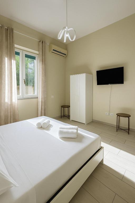 una camera da letto con un grande letto bianco e una TV a schermo piatto di Room Raffinata Stile e Comfort a Salerno