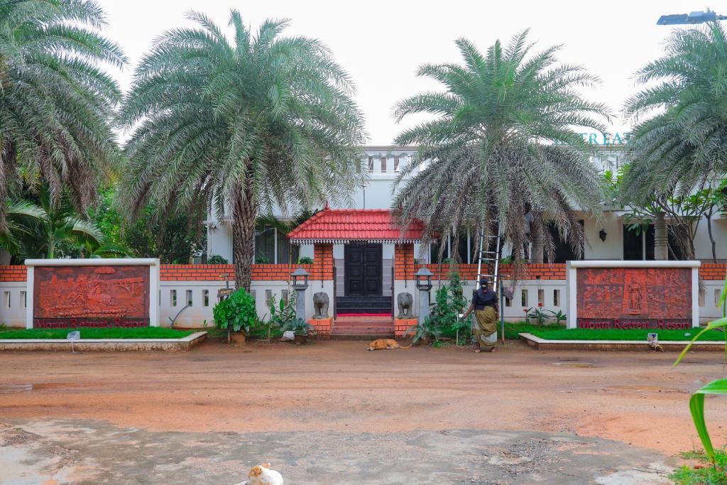Ein Mann steht vor einem Gebäude mit Palmen in der Unterkunft Mount Retreat Resorts - Madurai in Madurai