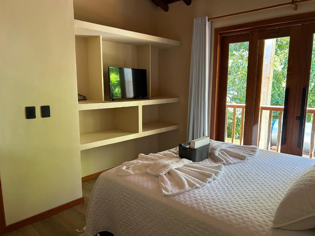 una camera da letto con un letto con una tv e una finestra di Casa Trancoso is full-service, new house, 10 mins walk to Beach & Quadrado a Porto Seguro