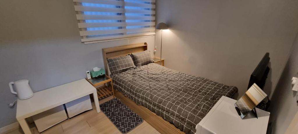 a small bedroom with a bed and a desk at Bombay Residence SNU Nakseongdae Station in Seoul