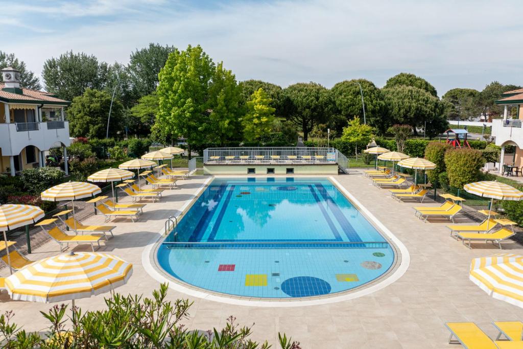 a swimming pool with chairs and umbrellas at Residence Brenta in Bibione
