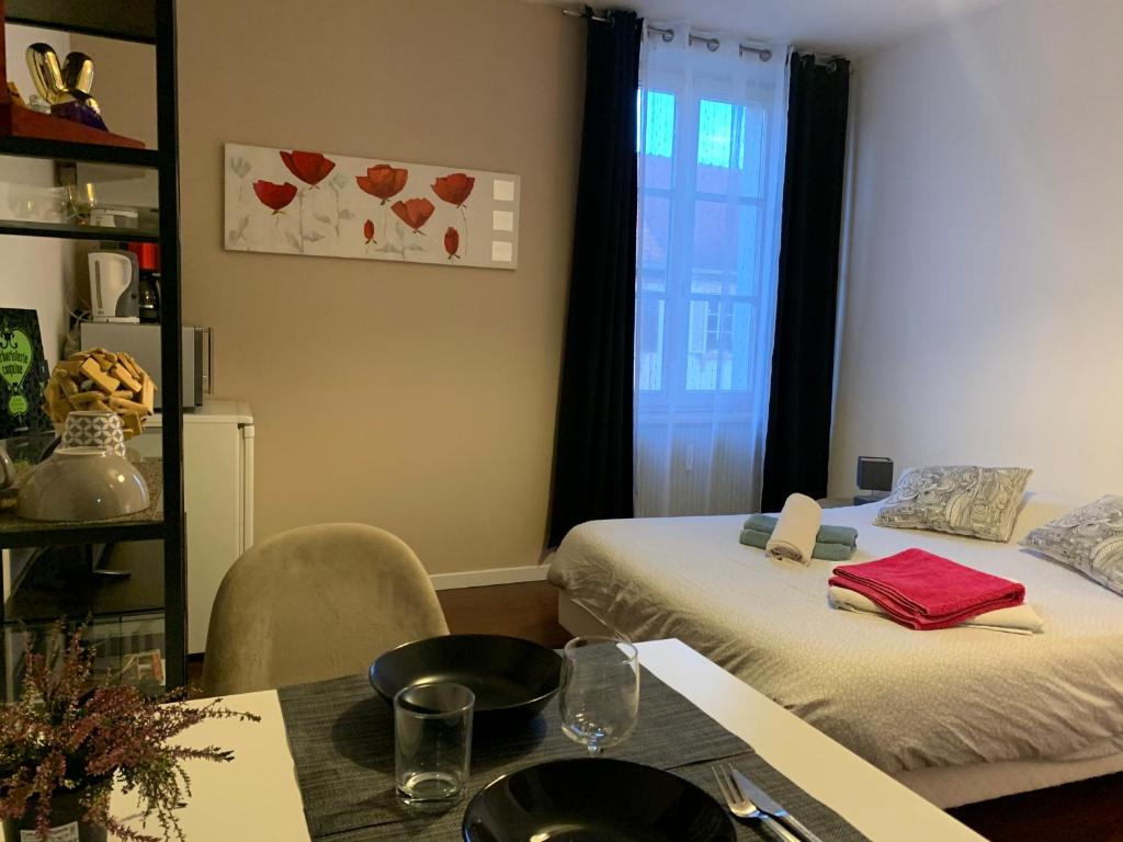 ein Zimmer mit zwei Betten und einem Tisch und einem Fenster in der Unterkunft Le Relais d Obernai in Obernai
