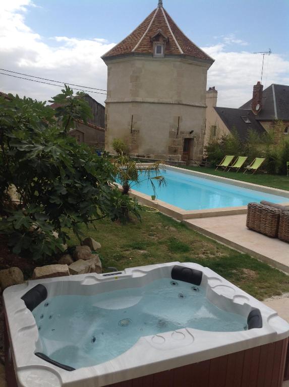 una bañera en un patio junto a una piscina en Le Colombier de la Graverie en Senots