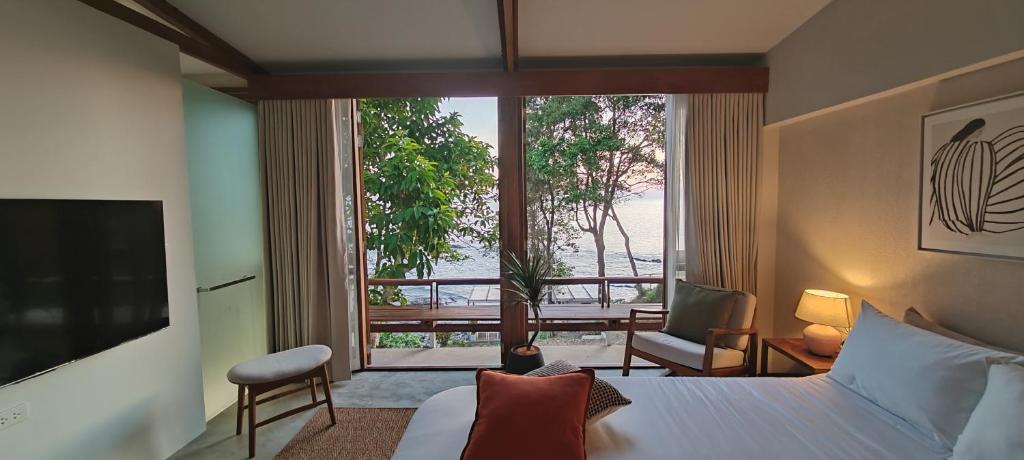a hotel room with a bed and a large window at Pebble Lanta - Seaview Stay in Ko Lanta