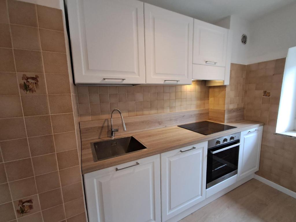 a kitchen with white cabinets and a sink at La Casa di Elvira-Primo Piano in Piaia