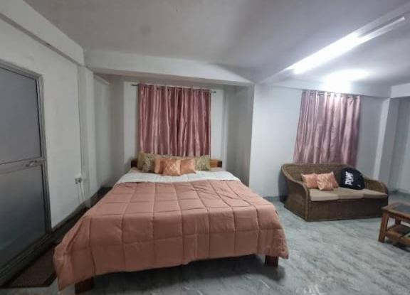 a bedroom with a large bed and a couch at Dzükou Guest House in Kohīma