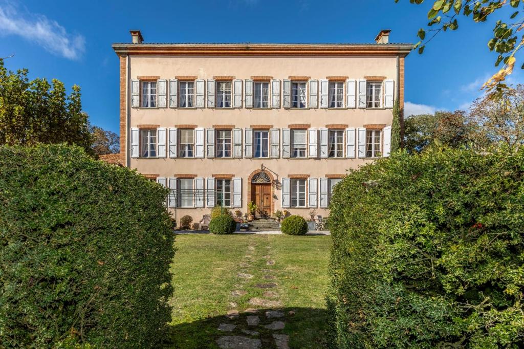 Una finca con un gran edificio con arbustos. en Château du pegulier location intégrale, en Montaut-de-Crieux