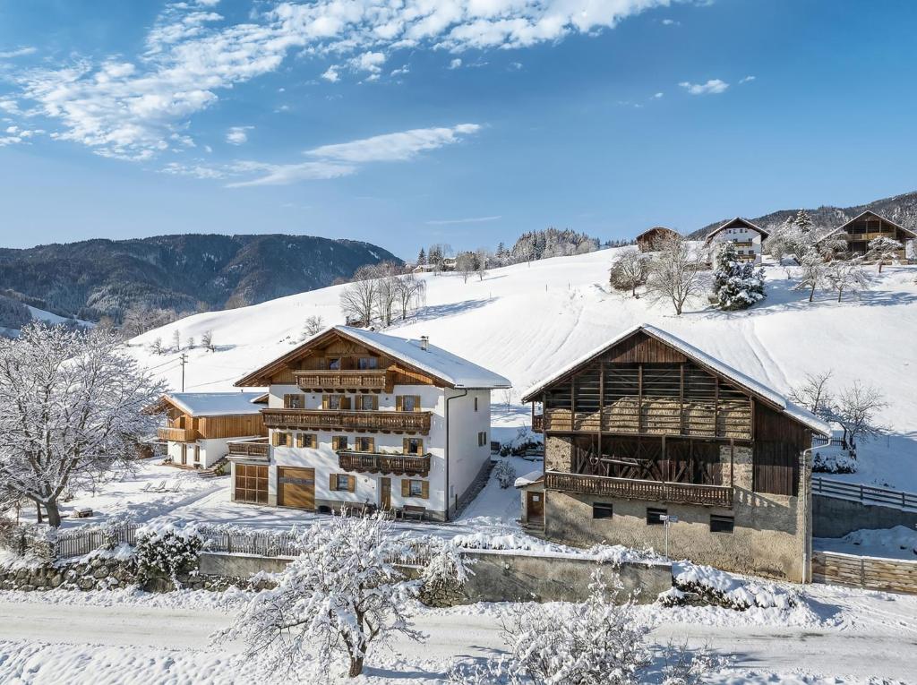 a house in the snow with mountains in the background at HAUSERHOF Farmhouse with Dolomite View in Villandro